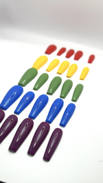 A top-down product display featuring five different sets of long, high-gloss press-on nails neatly arranged in parallel rows on a crisp white surface. The rows show a vibrant variety of solid colors including deep purple, royal blue, olive green, banana yellow, and cherry red, all showcasing a smooth gel structure and a flawless glossy finish.