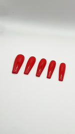 A top-down product photograph showing a set of five long, high-gloss cherry red press-on nails arranged neatly in a row. The salon-grade gel nails are displayed on a clean, solid white background, showcasing their crisp shape, rich solid red color, and a flawless, reflective glass-like top coat.